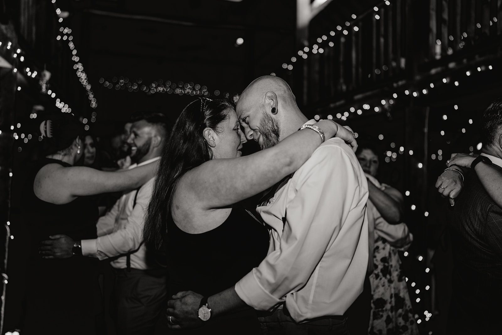 Black and white photograph of string light canopy inside a New England barn wedding venue