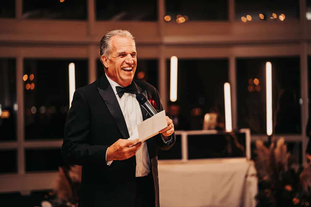 Father of the bride giving a toast beneath pixel tube lighting at a New England wedding