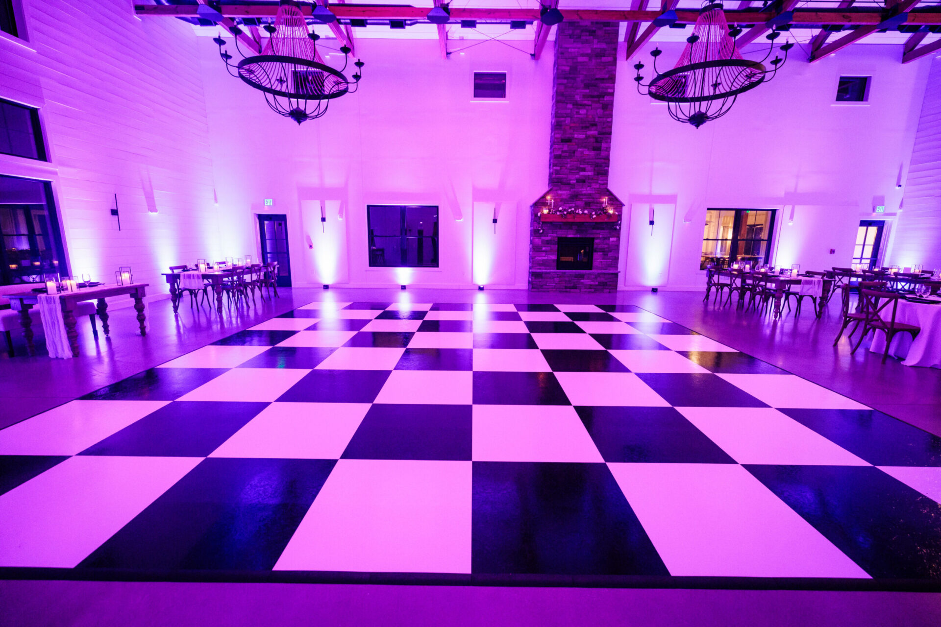 Black and white checkerboard dance floor with purple uplighting at a Boston wedding reception